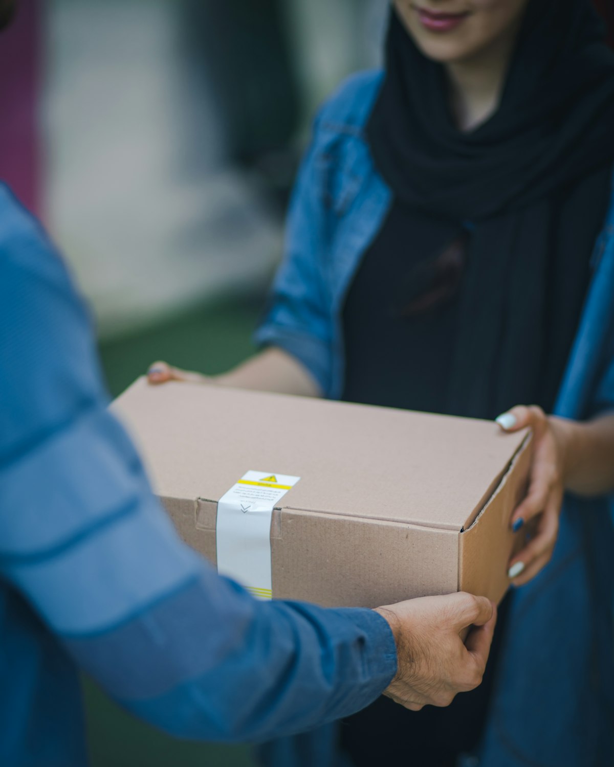 Courier handing a cardboard parcel to a customer