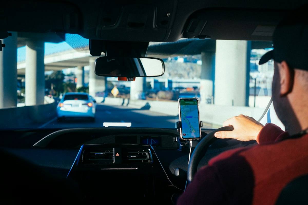Driver following a navigation app on a phone mounted on the dashboard
